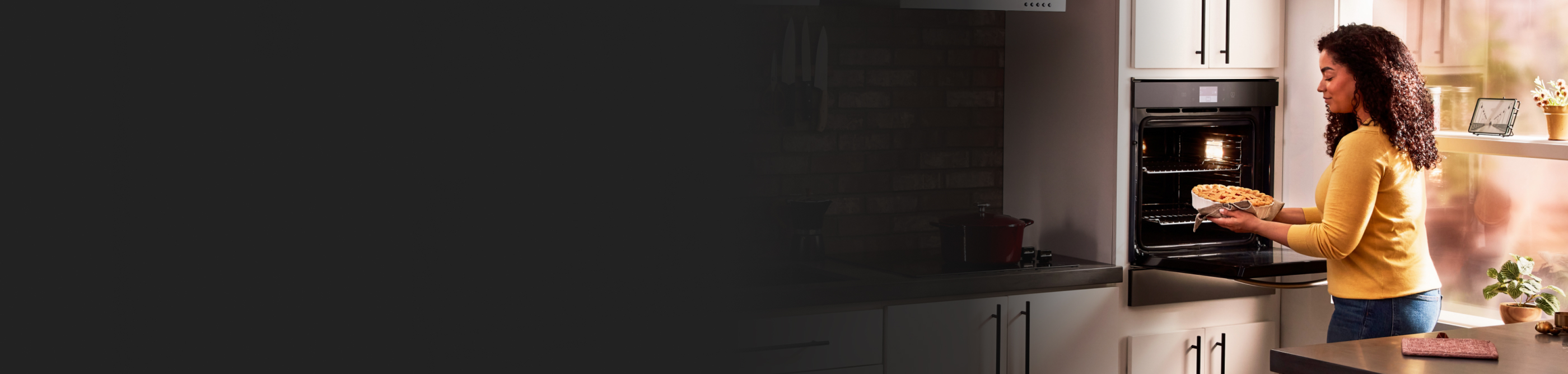 A woman pulling a baked dish out of a single wall oven