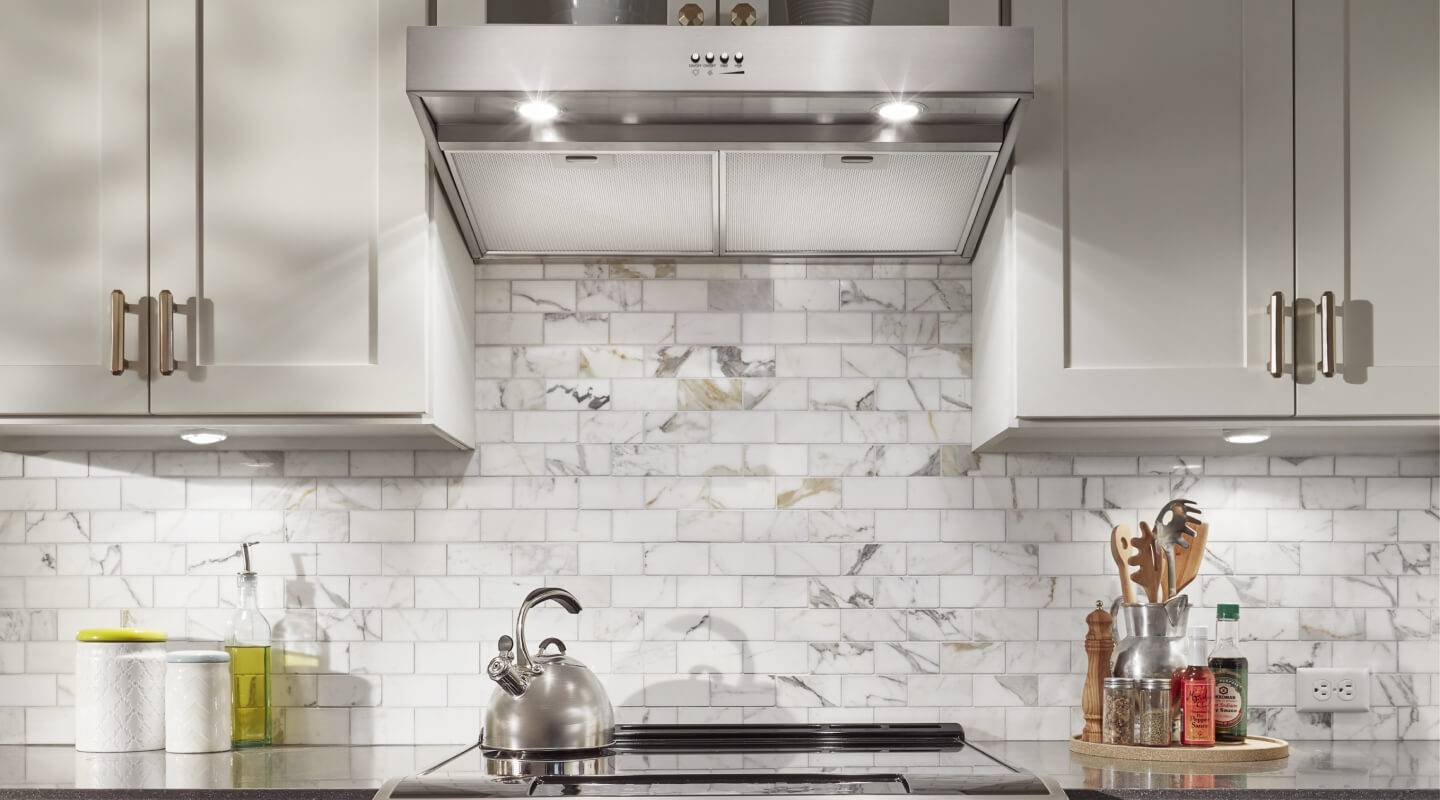  The interior of a kitchen with tiled walls and an under cabinet range hood