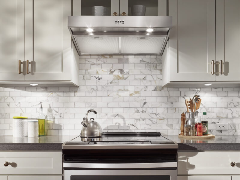  The interior of a kitchen with tiled walls and an under cabinet range hood