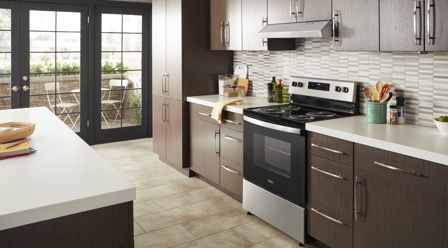 The interior of a kitchen with an electric range and under cabinet range hood