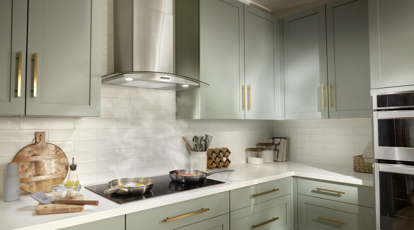 A Whirlpool® Chimney Wall Mount Range Hood and Range in a kitchen