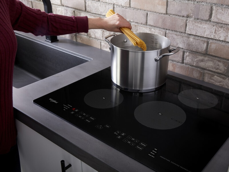 Person adding pasta to a pot of water
