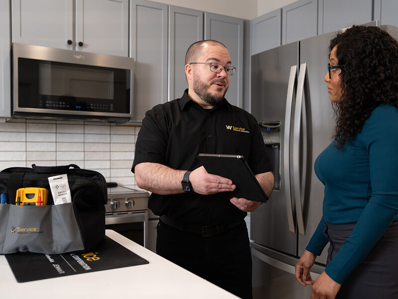 A technician helping a woman in her kitchen A technician helping a woman in her kitchen