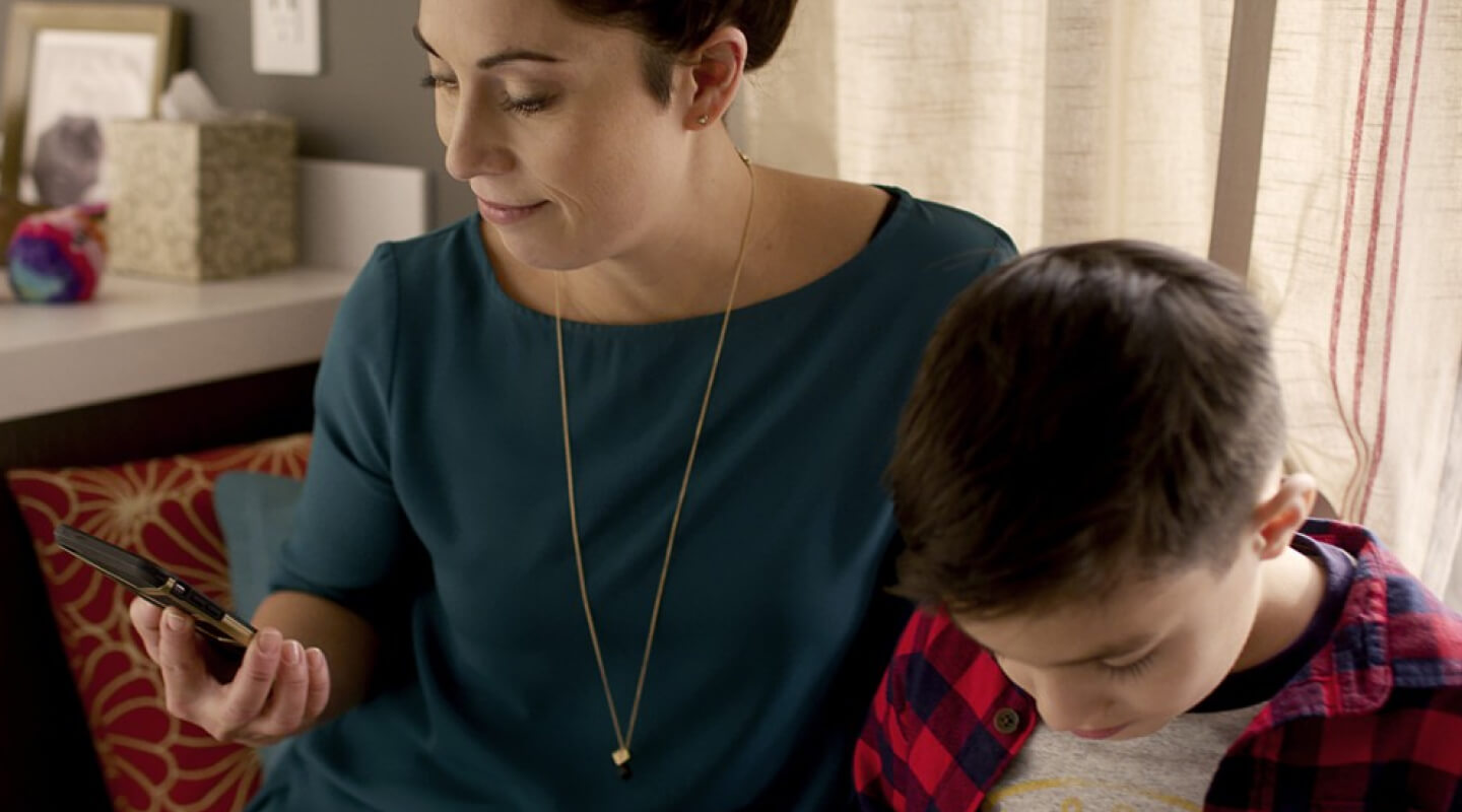 Woman looking at her phone sitting next to her son 
