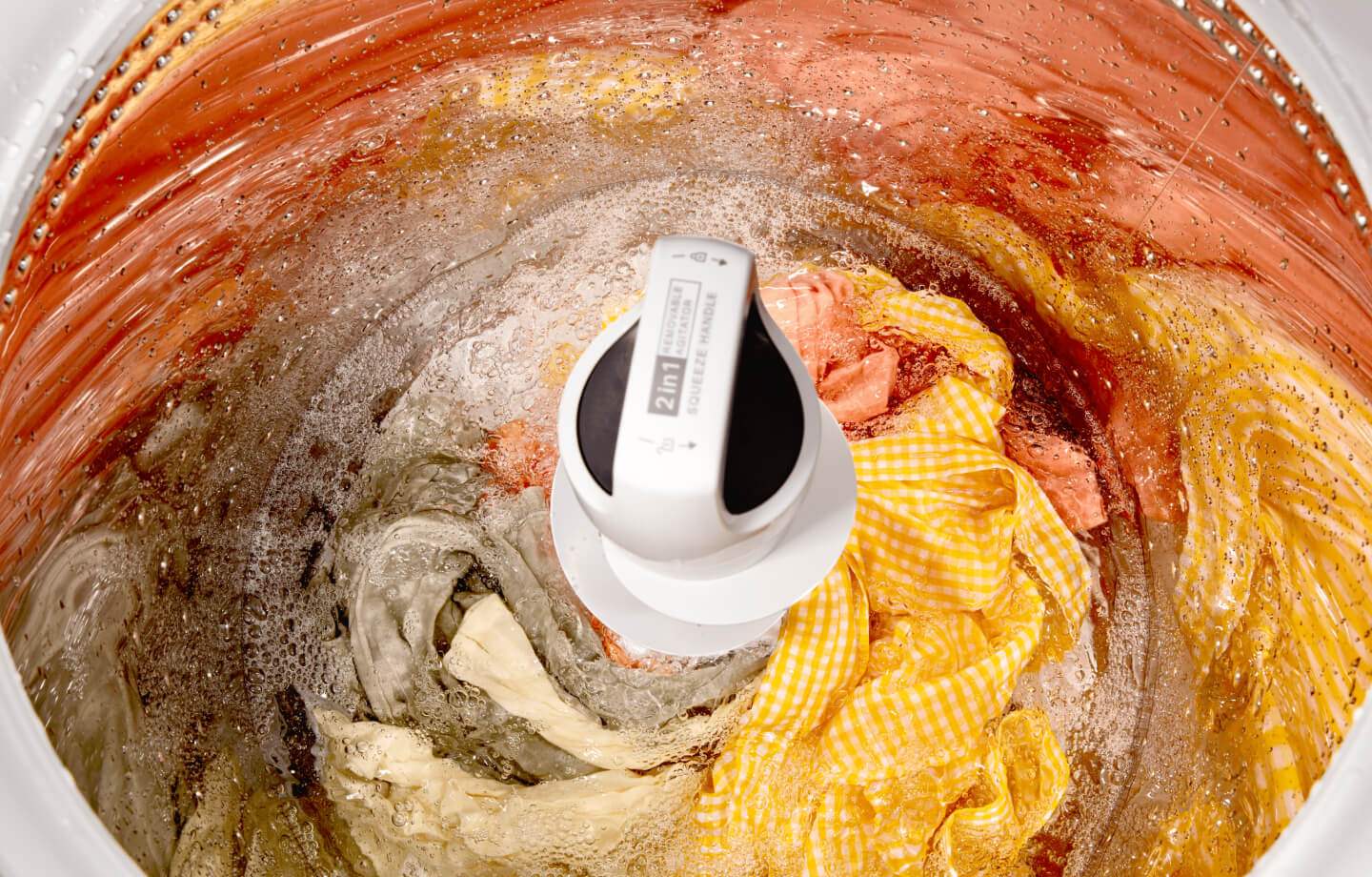 A Whirlpool® Top Load Washer with 2 in 1 Removable Agitator open with clothes inside A Whirlpool® Top Load Washer with 2 in 1 Removable Agitator open with clothes inside