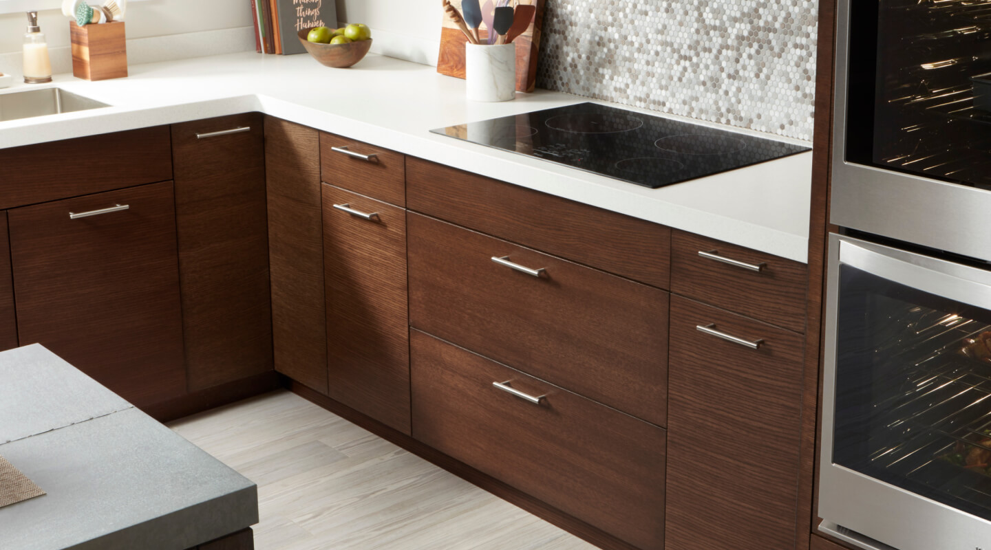 Whirlpool® electric cooktop and dark wooden cabinetry with white countertops