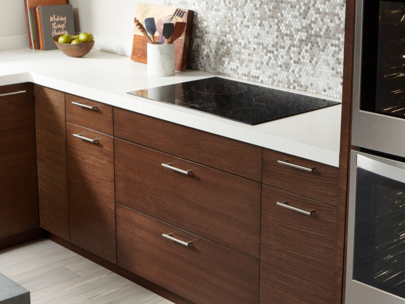 Whirlpool® electric cooktop and dark wooden cabinetry with white countertops