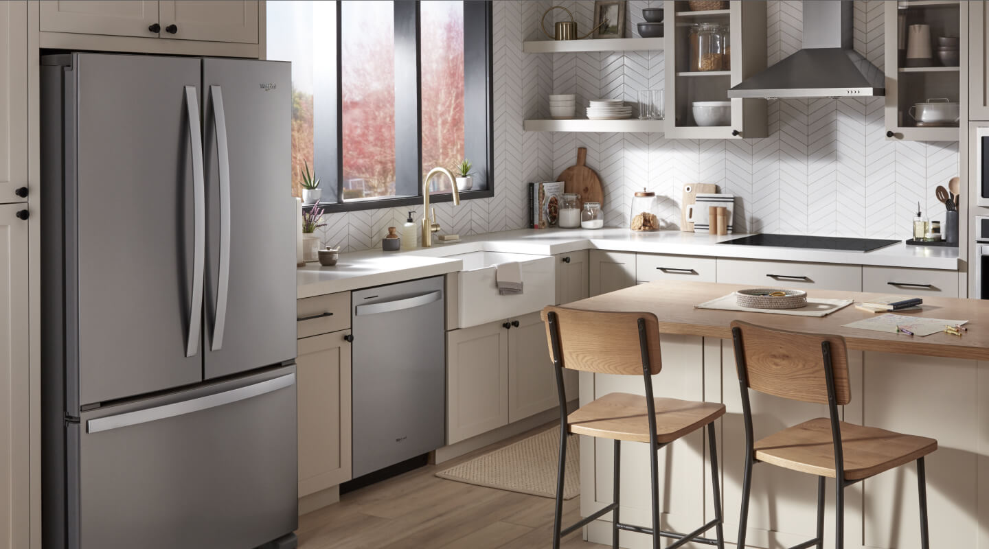The inside of a kitchen with stainless steel appliances and a wooden kitchen counter and chairs