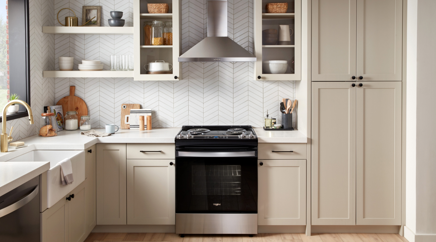 A stainless steel range hood above a black range A stainless steel range hood above a black range