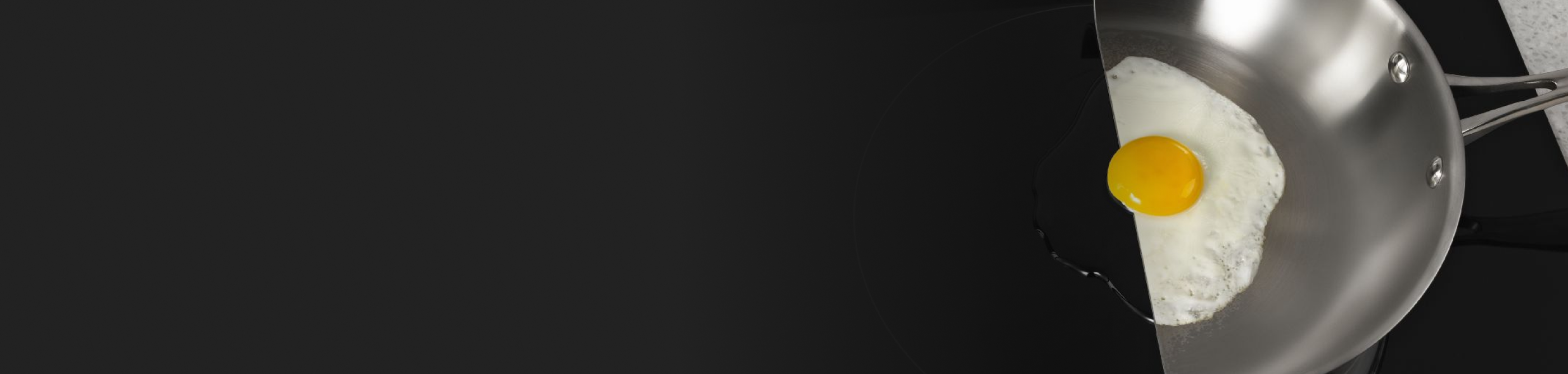 An egg cooking on a pan cut in half on an induction cooktop