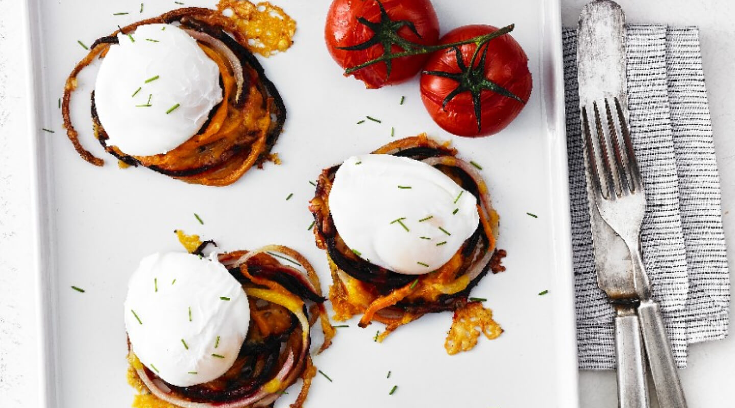 Poached eggs on a white plate with some tomatoes on the side