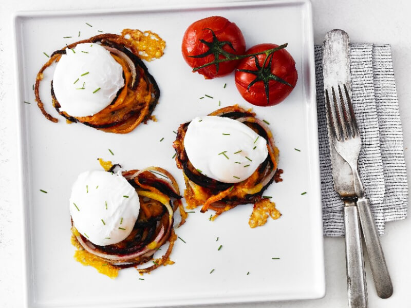 Poached eggs on a white plate with some tomatoes on the side