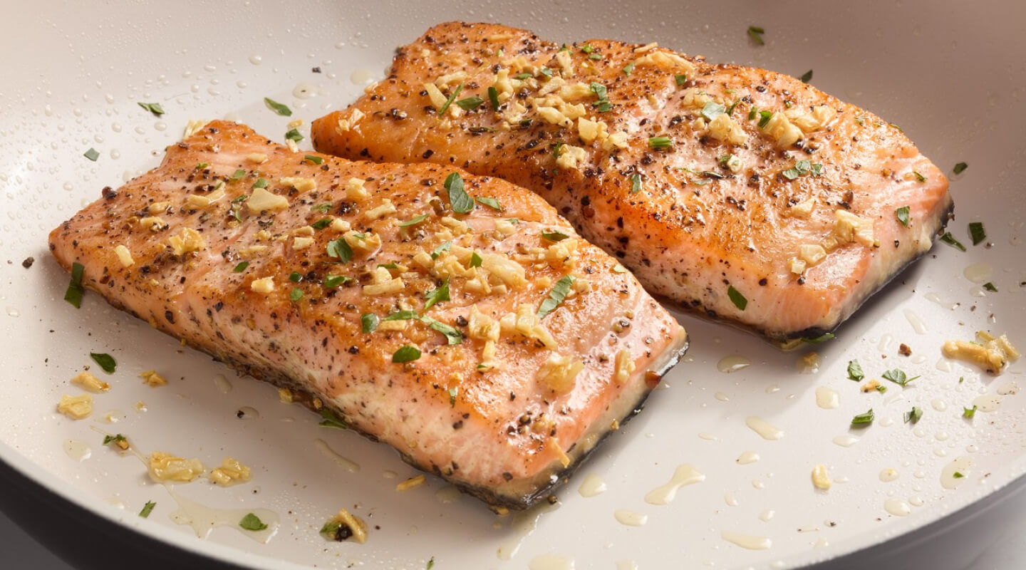Two pieces of cooked salmon on a white plate