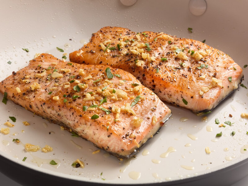 Two pieces of cooked salmon on a white plate