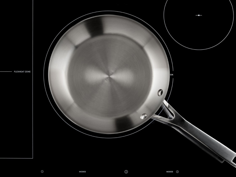 An empty, stainless steel pan on a glass cooktop surface