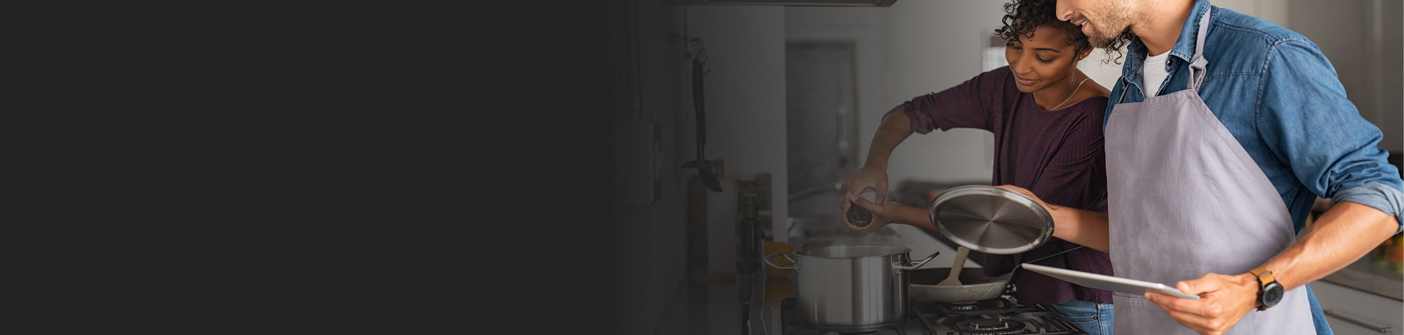 A man and woman cooking together at a range