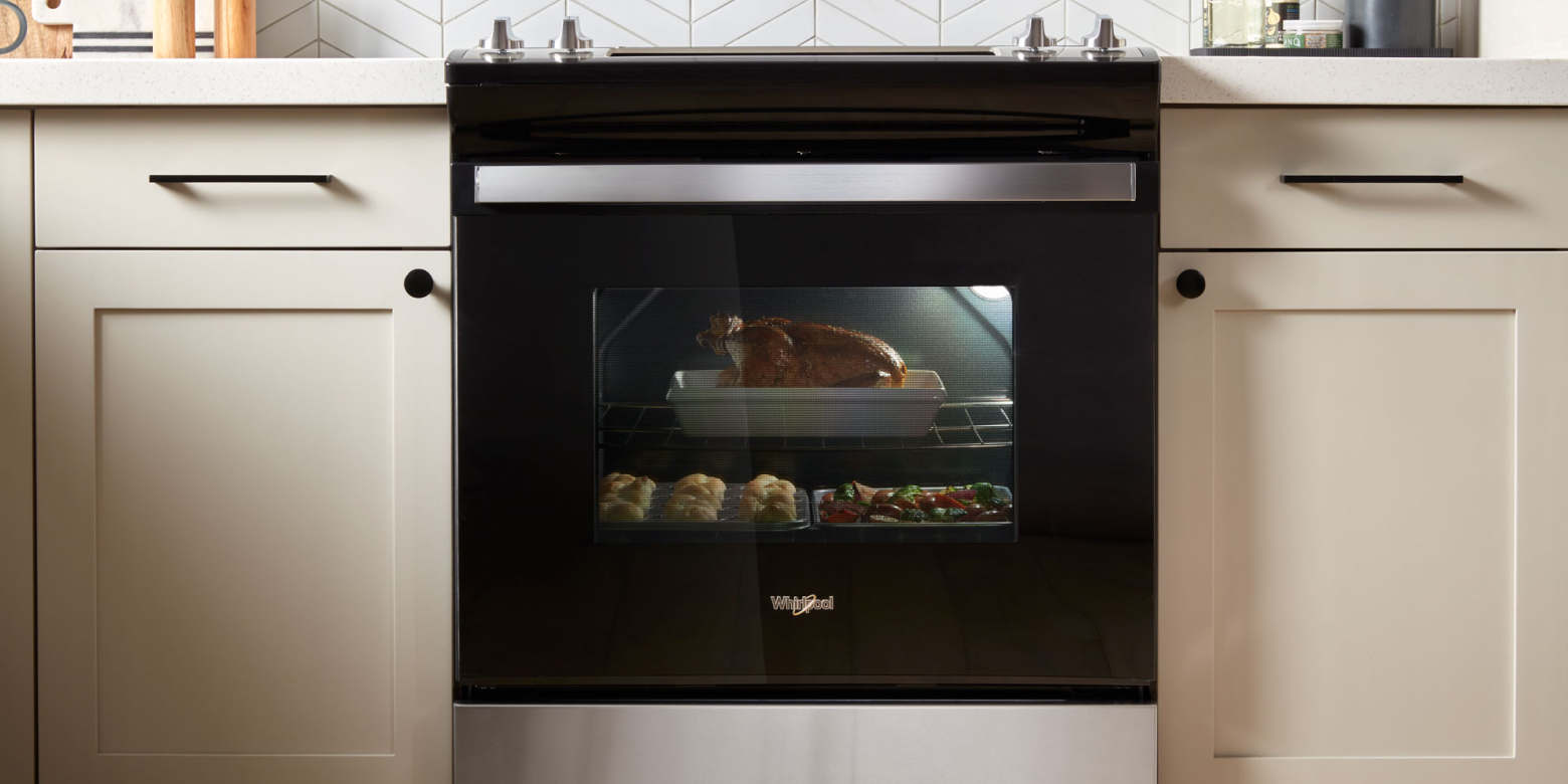 A black slide-in range with various dishes baking inside