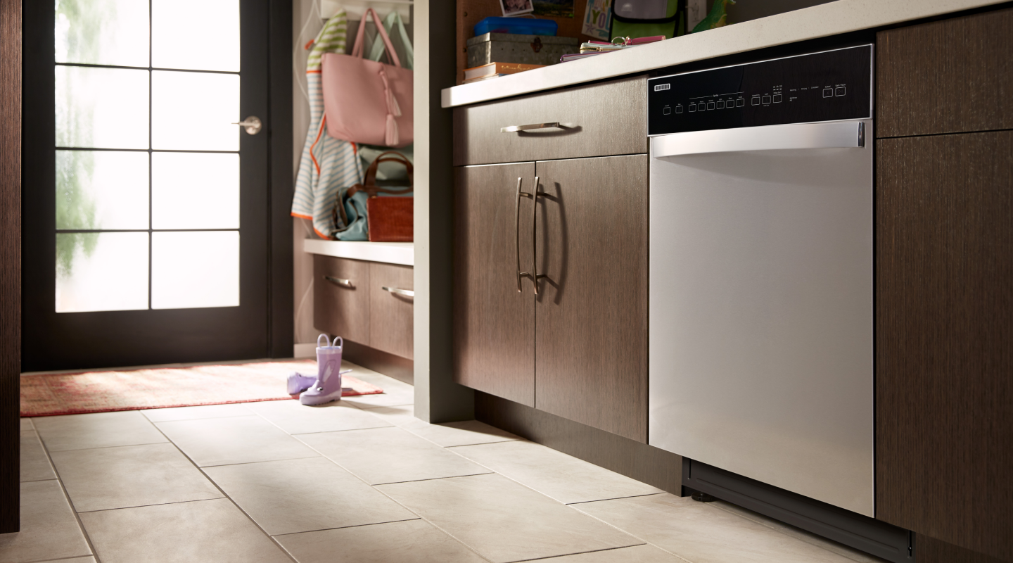 A stainless steel dishwasher in a kitchen with brown cabinets