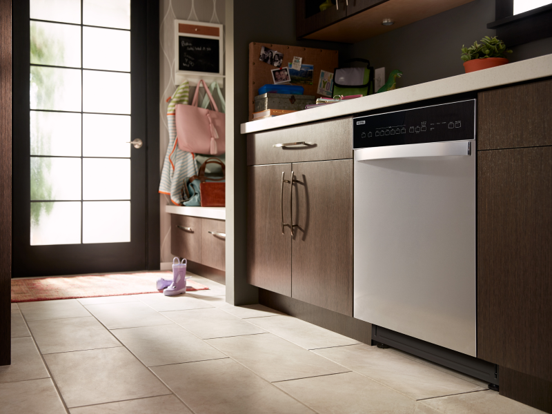 A stainless steel dishwasher in a kitchen with brown cabinets