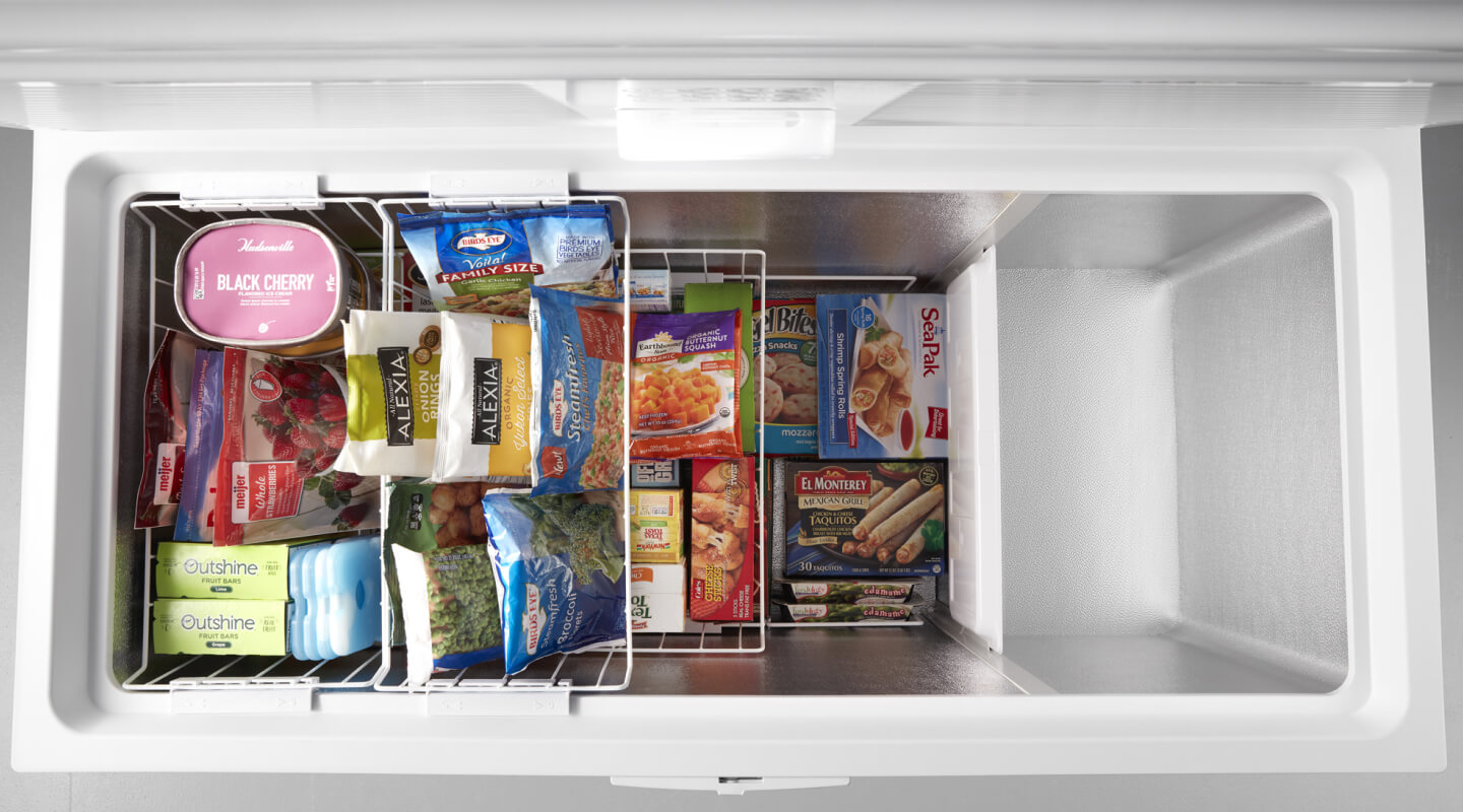 An open Whirlpool® chest freezer with a variety of frozen foods inside