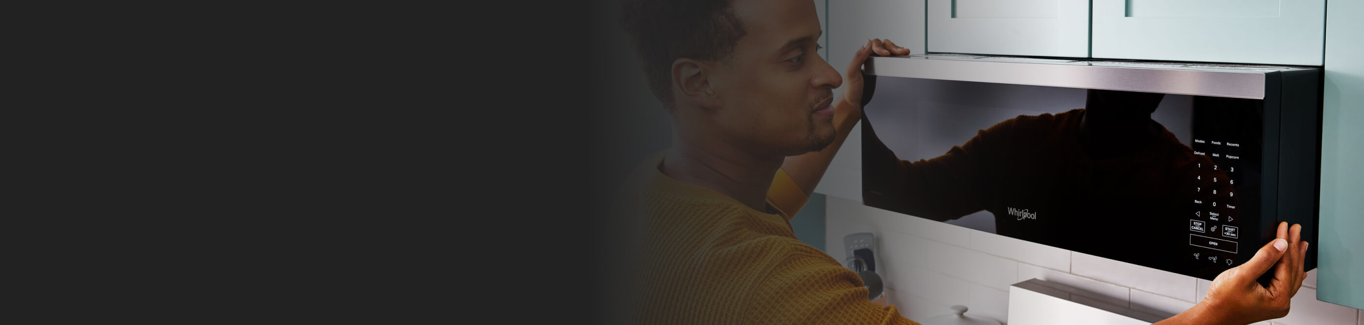 Person positioning a microwave over a stove