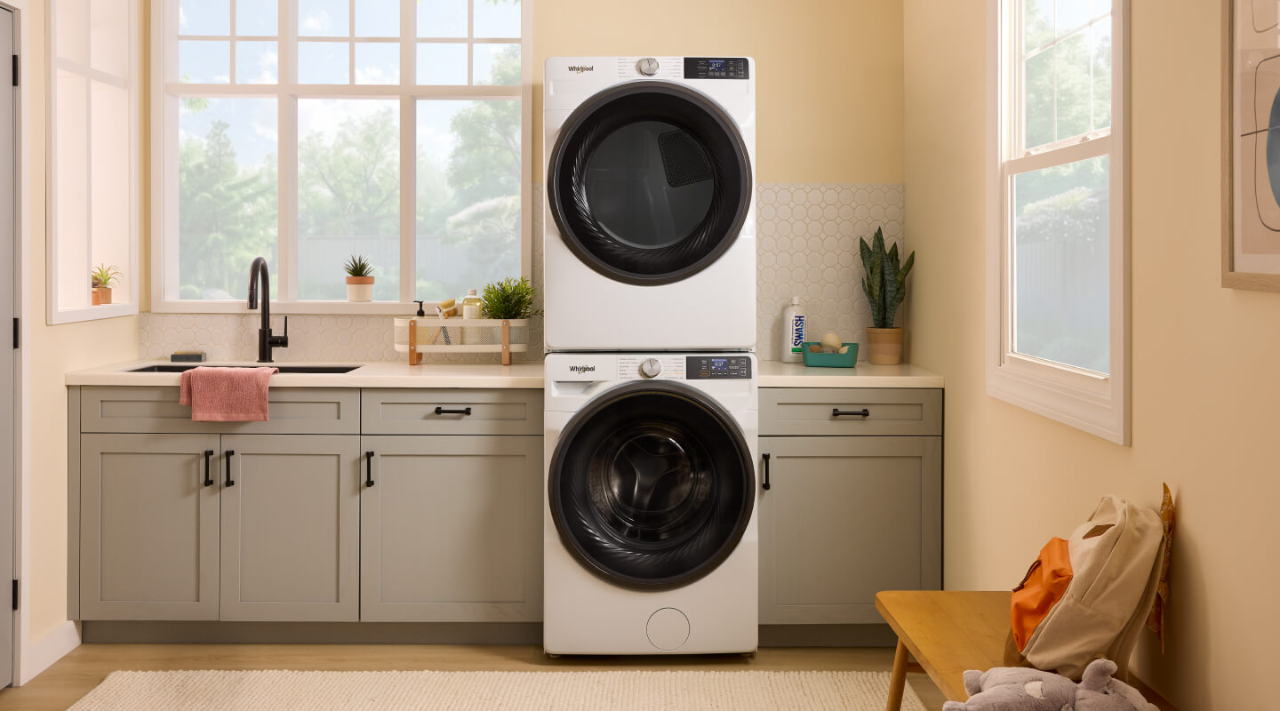 A stacked Whirlpool® Front Load Washer and Dryer in a laundry room
