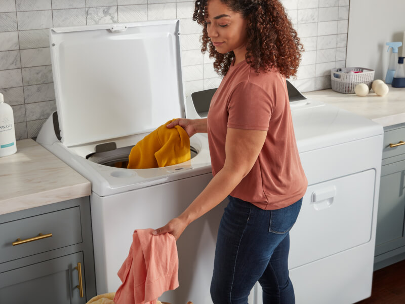 Person removing clothes from a top load washing machine Person removing clothes from a top load washing machine