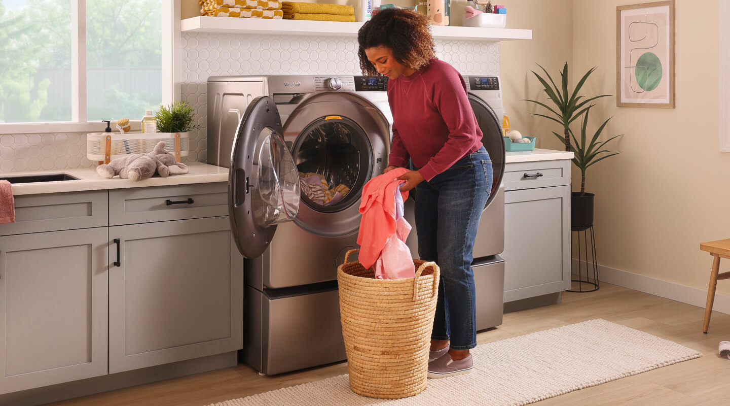 A person loading laundry into a washing machine