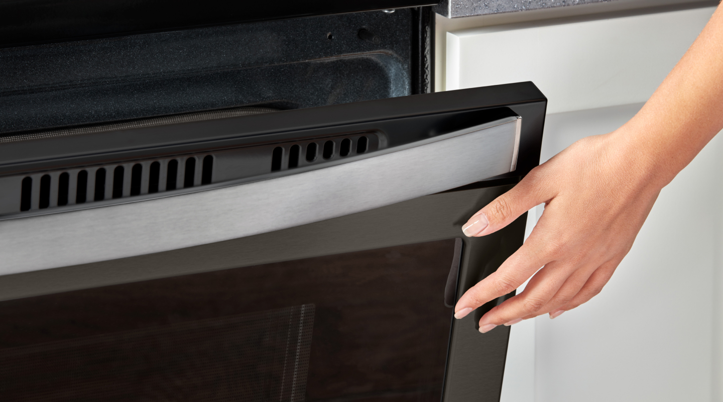 Person closing a slightly opened oven door Person closing a slightly opened oven door