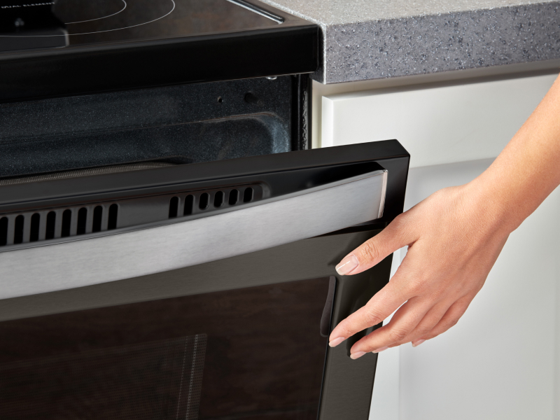 Person closing a slightly opened oven door Person closing a slightly opened oven door
