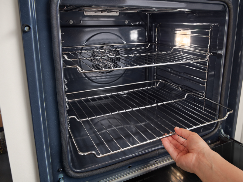 Hand removing racks from inside oven Hand removing racks from inside oven