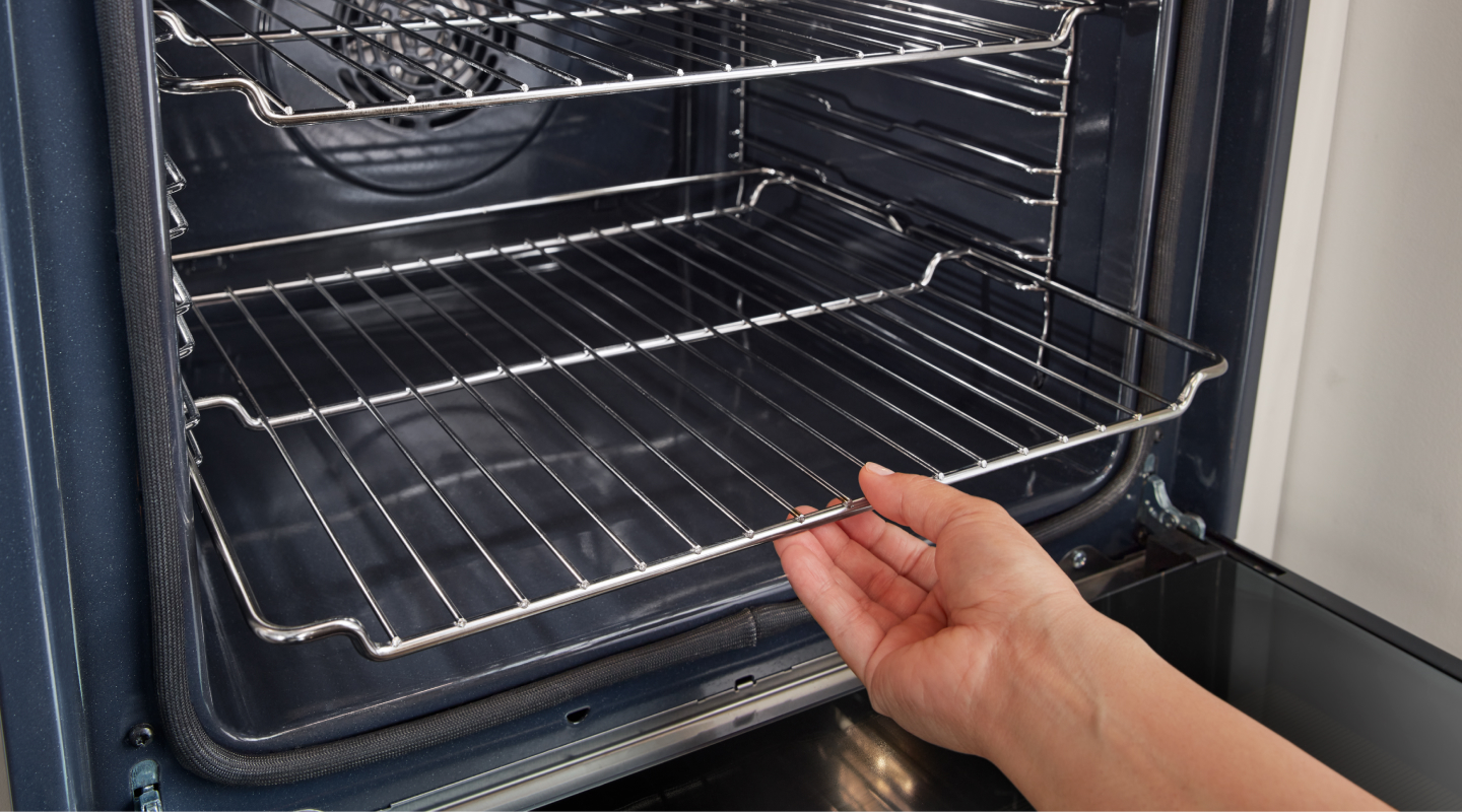 Hand removing racks from inside oven Hand removing racks from inside oven