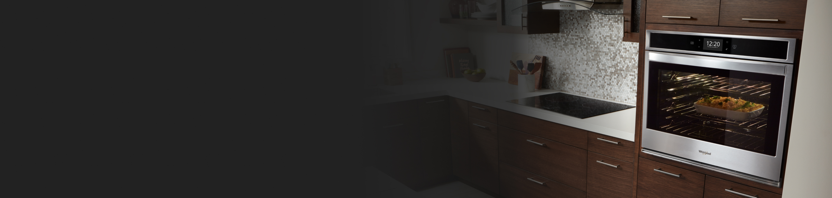 Whirlpool® oven set into wood paneling with casserole baking inside