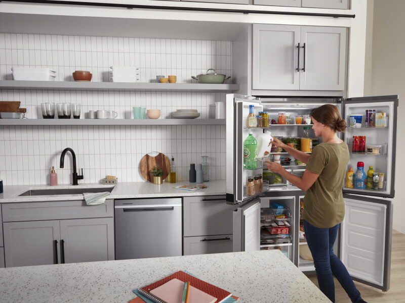 A woman removing a gallon of milk from her open refrigerator in her kitchen