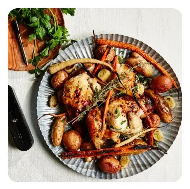 A plate of roasted chicken, potatoes and carrots with herbs