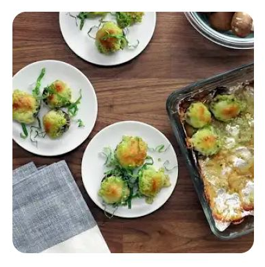 Three white plates with green pesto stuffed mushroom caps