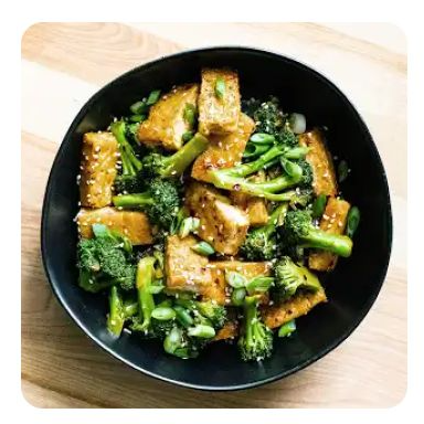 A black bowl with crispy, sautéed tofu and broccoli