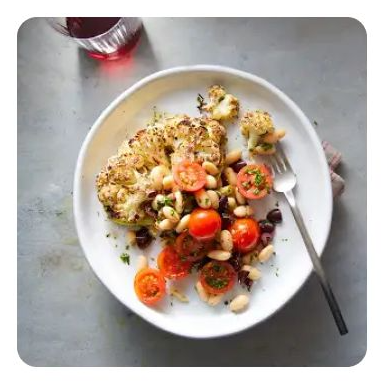 Charred cauliflower steak with cherry tomatoes on a plate