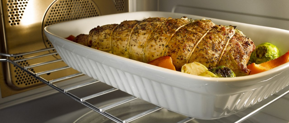 Roasted chicken and vegetables in a baking dish inside an oven