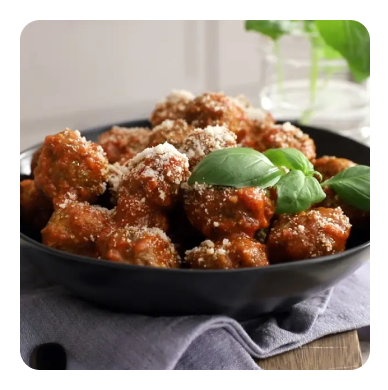 A bowl of meatballs in spaghetti sauce topped with basil