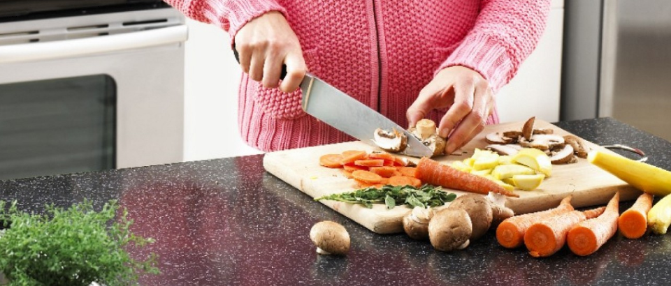 A person chopping vegetables on a wooden cutting board