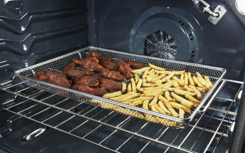 Inside oven with food cooking in an air fry basket.