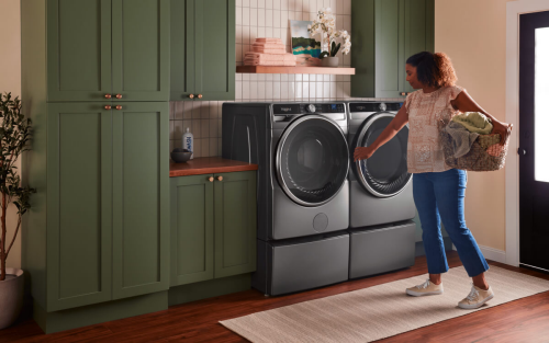 Person holding a laundry basket in front of a front load washer and dryer set