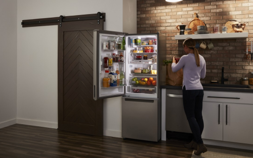 A woman next to a bottom-freezer fridge