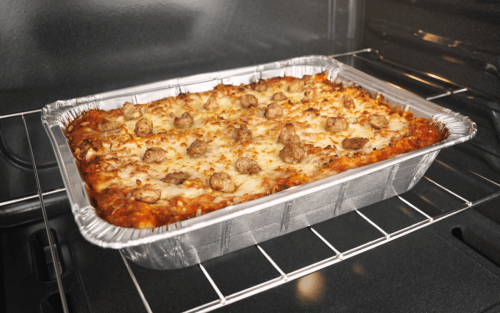 Lasagna cooking in a foil pan in the oven