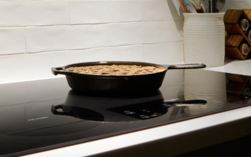 A cast iron pan on a black ceramic glass cooktop.