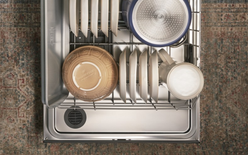 Open dishwasher filled with bowls and dishes