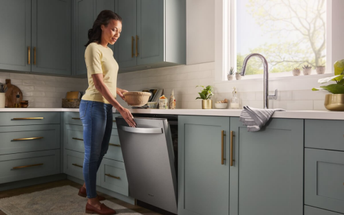 A person opening a dishwasher in a kitchen