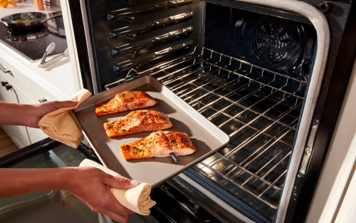 Person removing pan of food from oven.