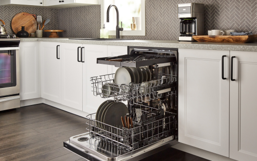 An open Whirlpool® dishwasher loaded with dishes.